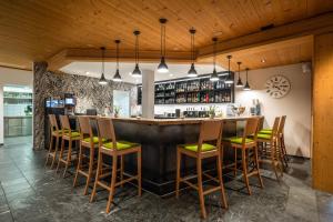 a bar in a restaurant with wooden ceilings and wooden stools at Hotel Alpina in Schiers