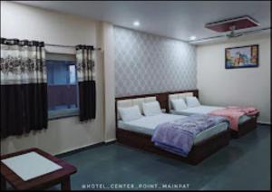 a bedroom with two beds and a table at Hotel Center Point Kamleshwarpur 