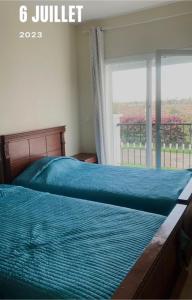- un lit avec une couette bleue devant une fenêtre dans l'établissement Appartement à résidence Ap8 , marina , saidia, à Berkane