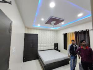 two men are standing in a room with a bed at Hotel Center Point Kamleshwarpur 