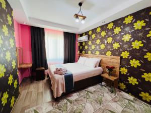 een slaapkamer met een bed met bloemen aan de muur bij aria plus ev-otel in Çiftlikköy