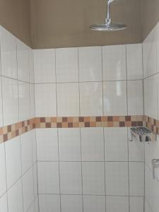 baño de azulejos blancos con ducha con luz en Looks cottages self catering apartments, en Kasane