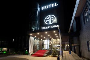 un hotel con un cartel en la parte delantera de la noche en Tauke Khan Plaza, en Shymkent