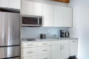 uma cozinha com armários brancos e um frigorífico de aço inoxidável em South End studio w building wd nr dining BOS-903 em Boston