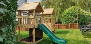 a wooden playset with a slide in a yard at Ye Olde Original Withy Trees in Bamber Bridge