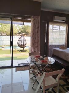 ein Wohnzimmer mit einem Tisch und einem Bett in der Unterkunft Looks cottages self catering apartments in Kasane