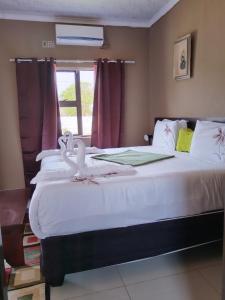 a bedroom with a large white bed with a window at Looks cottages self catering apartments in Kasane