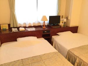 a hotel room with two beds and a desk with a television at Kisyaba Hotel in Kagoshima
