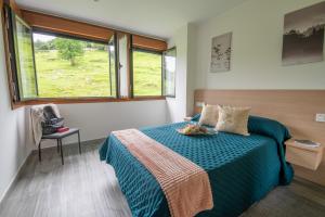sypialnia z łóżkiem z niebieskim kocem i oknem w obiekcie Apartamentos Spa Las Caldas y Spa El Balneario w mieście Oviedo