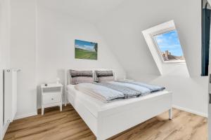 a white bedroom with a bed and a window at Altstadt-Refugium unterm Dach Goslar in Goslar