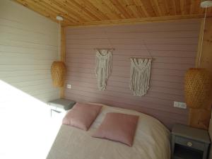 a bedroom with a bed with pink pillows on it at les lodges finlandais de la tortue permacole fine dentelle in Champclause