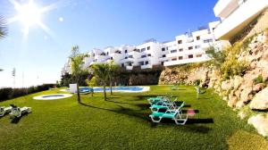 um grupo de cadeiras sentadas na relva perto de um edifício em Apartment Mar de Nerja Beach em Nerja