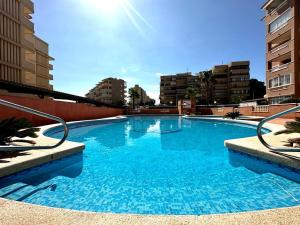 uma grande piscina azul com edifícios ao fundo em Arenales del Sol Beach Apartment em Arenales del Sol