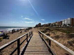 um calçadão de madeira que leva a uma praia com pessoas nele em Arenales del Sol Beach Apartment em Arenales del Sol