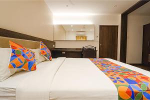 FabHotel Karpagam في كويمباتور: غرفة نوم مع سرير كبير مع وسائد ملونة