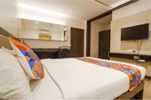 FabHotel Karpagam في كويمباتور: غرفة نوم مع سرير وتلفزيون على الحائط