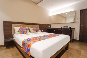 FabHotel Karpagam في كويمباتور: غرفة نوم مع سرير أبيض كبير مع وسائد ملونة