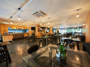 ein Restaurant mit Tischen und Stühlen und eine Küche in der Unterkunft Galleria 12 Sukhumvit Bangkok by Compass Hospitality in Bangkok