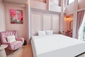 um quarto com uma cama branca e uma cadeira rosa em 星澄風旅 Zela Design Hotel em Kaohsiung