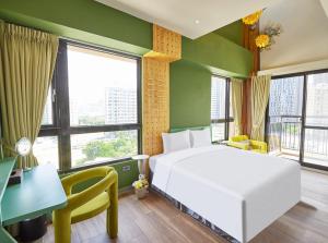 a bedroom with a white bed and a desk and windows at 星澄風旅 Zela Design Hotel in Kaohsiung