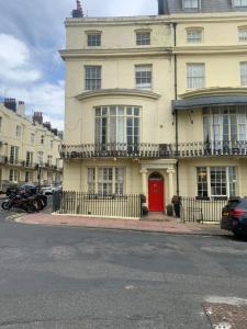 a large white building with a red door on a street at Entire apartment in central Brighton in Brighton & Hove