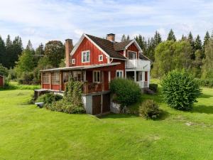 una casa roja en un campo verde con árboles en Holiday Home Hultet - VGT098 by Interhome en Mullsjö