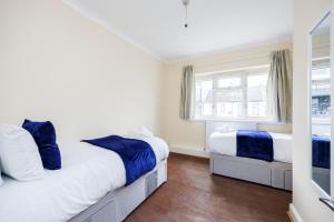 a bedroom with two beds and a window at 2 Bedroom House by AV Stays Short Lets Croydon With Free Wi-Fi in South Norwood