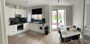 a kitchen with white cabinets and a table with chairs at Supreme Apartments in Keighley