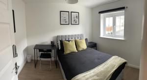 a bedroom with a bed with yellow pillows and a table at Supreme Apartments in Keighley