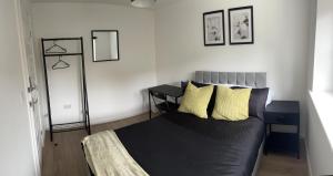 a bedroom with a black bed with yellow pillows at Supreme Apartments in Keighley