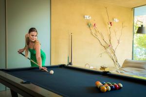 a woman playing pool with a cue on a pool table at Ortenia Apartments in Nature in Podčetrtek