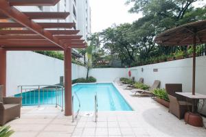 a swimming pool with chairs and an umbrella on a building at RedDoorz Premium at The Residences Olympia Makati in Manila