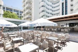 un patio al aire libre con mesas, sillas y sombrillas en Hotel Best Da Vinci, en Salou