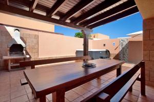 una mesa de madera y bancos en un patio con horno al aire libre en Villa Malva en Corralejo