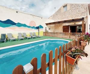 a swimming pool with chairs next to a building at Casa Rural Villa Margarita in Dosbarrios