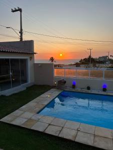 una piscina en un patio con la puesta de sol en el fondo en Villa do Nino en Canoa Quebrada