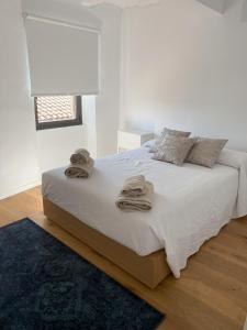 a white bedroom with a bed with towels on it at Fam de Vida in Gratallops