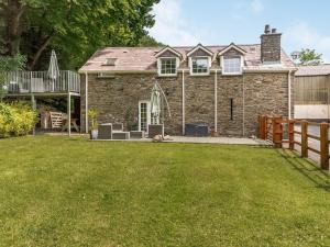 a stone house with a yard and a fence at Garden apartment in Llandysul