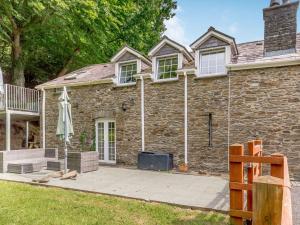 a stone house with a patio in front of it at Garden apartment in Llandysul