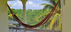 d'un hamac sur un balcon avec vue sur les arbres. dans l'établissement Gozié maison plein air et aéré, au Gosier