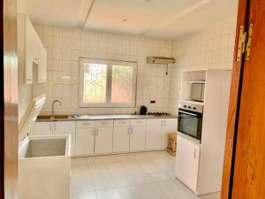 une cuisine avec des appareils électroménagers blancs et une fenêtre dans l'établissement Résidence Toubab, à Toubab Dialo