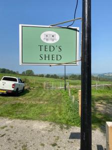 a sign on a pole with a car parked in a field at Ted's Shed in Bishop Auckland