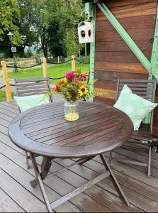 a wooden table with a vase of flowers on a deck at Ted's Shed in Bishop Auckland