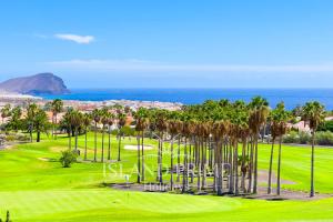 vista su un campo da golf con palme e sull'oceano di Holiday Garden House in Golf del Sur a San Miguel de Abona
