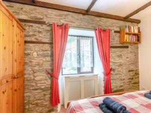 a bedroom with red curtains and a stone wall at The Stable in Llandysul