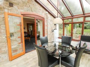 ein Esszimmer mit Glastisch und Stühlen in der Unterkunft Rowan Cottage in Shrewsbury