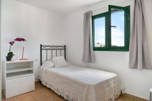 um quarto branco com uma cama e uma janela em San roque em Tinajo