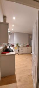 a kitchen with white cabinets and a wooden floor at A home away from home in Torquay