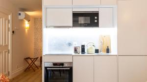 uma cozinha com armários brancos e um micro-ondas em Urban House Marquês by LovelyStay em Porto