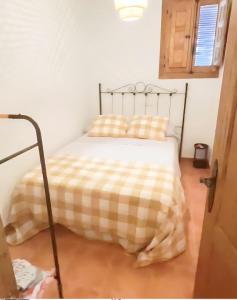 - une chambre avec un lit et une couverture en damier dans l'établissement CASA VALLE VERDE, à Lentegí